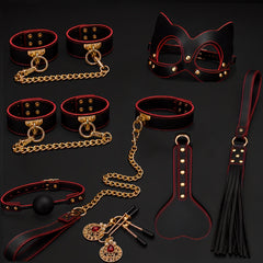 Flat lay of the Eclipse Ritual red and black 10-piece bondage kit with cuffs, collar, mask, gag, paddle, flogger, clamps and gold-tone hardware.