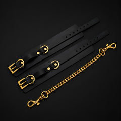 Flat lay of the Obsidian adjustable black vegan leather cuffs with polished metal buckles and hardware.